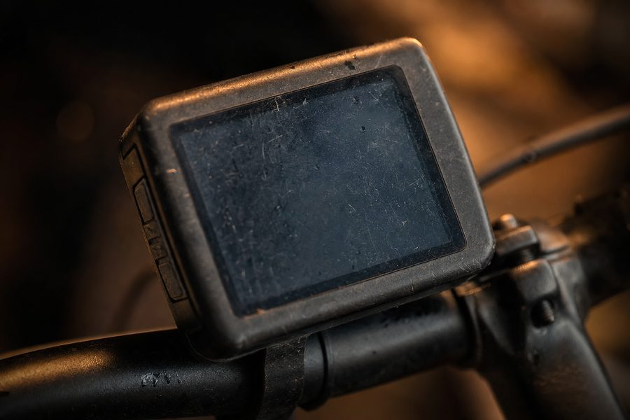 Ein zerkratztes, ausgeschaltetes E-Bike-Display am Lenker mit Regenspuren auf dem Kunststoff