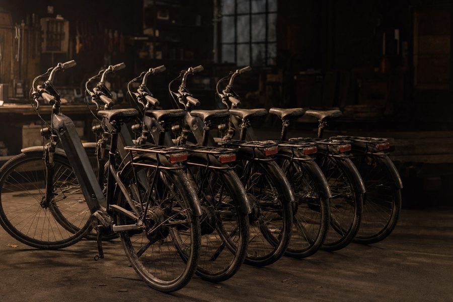 Sechs baugleiche Trekking-E-Bikes stehen aufgereiht in einem Depot