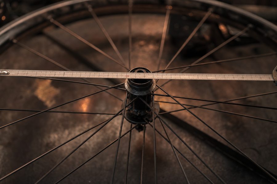 Ein Stahlmaßband liegt über dem Durchmesser eines flach liegenden Fahrradlaufrads