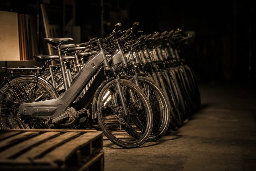 Eine lange Reihe nahezu baugleicher Trekking-E-Bikes in einem dunklen Lagergang