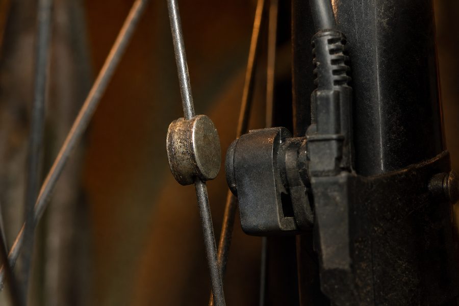 Ein gebrauchter Speichenmagnet neben dem Geschwindigkeitssensor an der Gabel eines Fahrrads