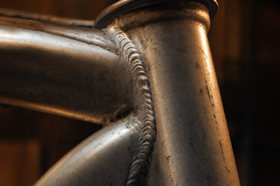 Nahaufnahme einer Schweißnaht am Steuerrohr eines Aluminiumrahmens mit sichtbaren Schweißwellen