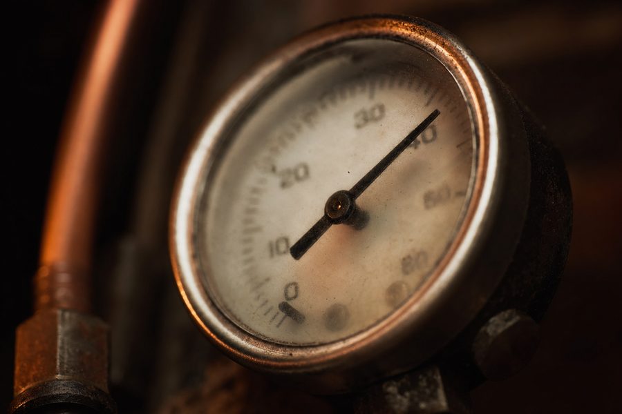 Das Zifferblatt eines analogen Manometers schräg fotografiert, die Nadel sichtbar