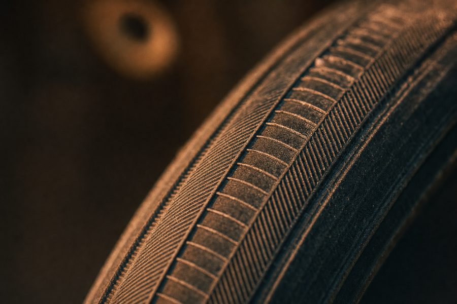 Nahaufnahme der geprägten Seitenwand eines gebrauchten Fahrradreifens im Streiflicht